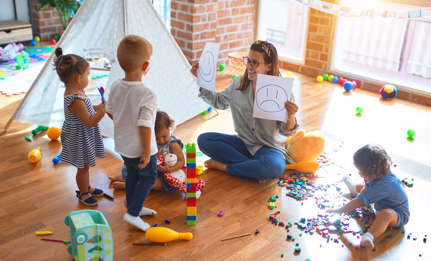 GettyImages-1212696582 Children playing with caregiver in playroom.