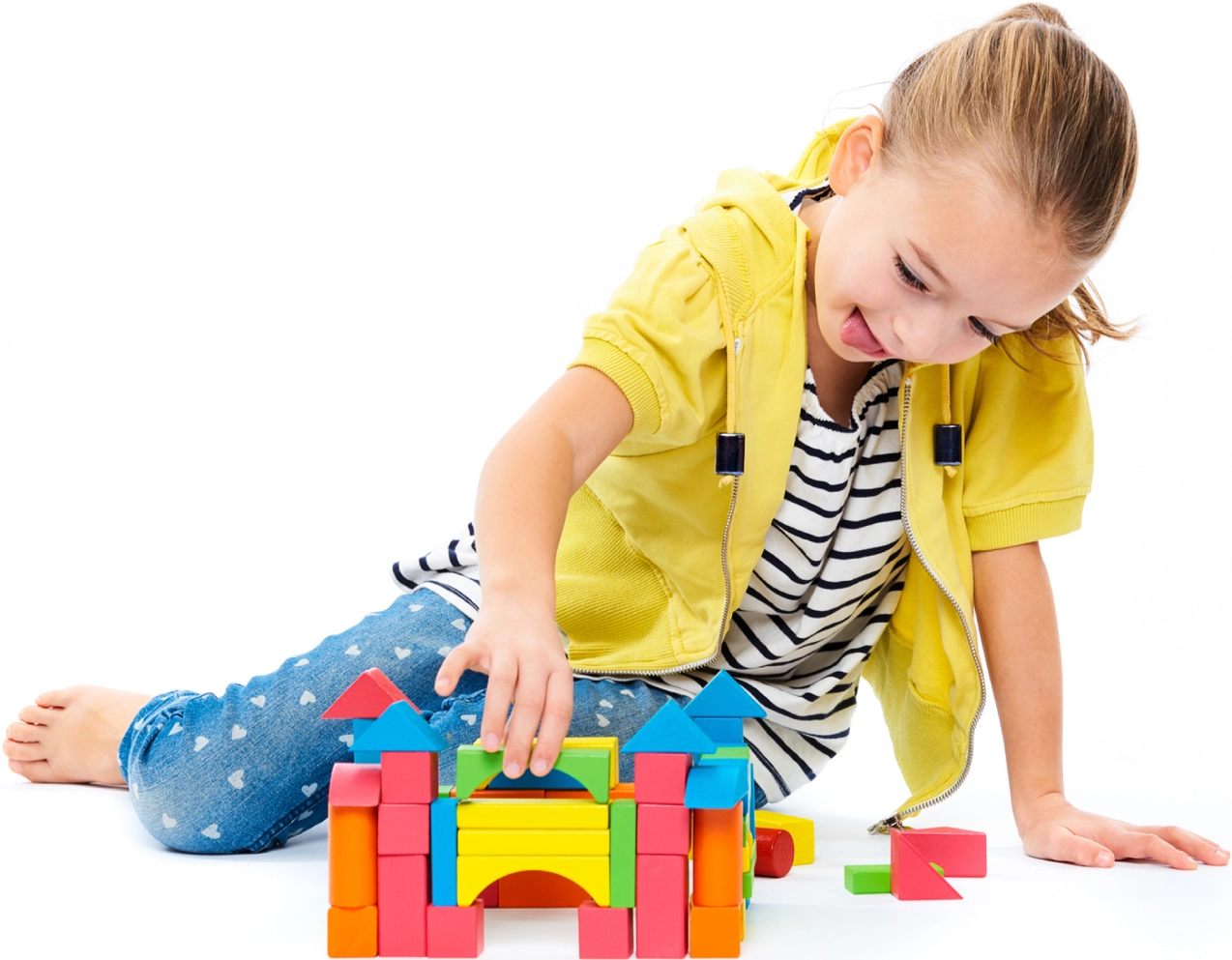 A little girl playing with blocks on the floor.