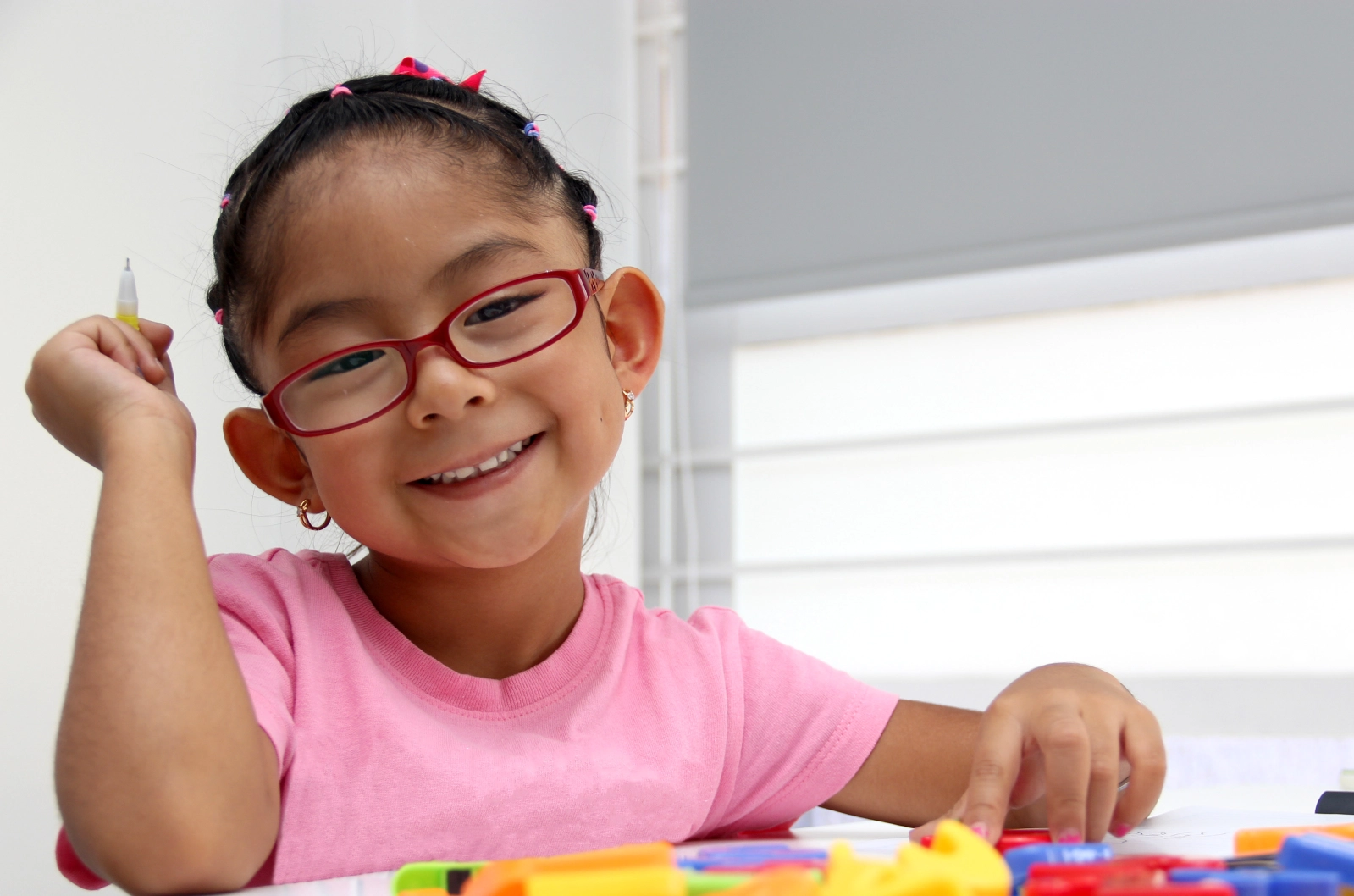 GettyImages-2185522419 Child smiling while drawing at a table.