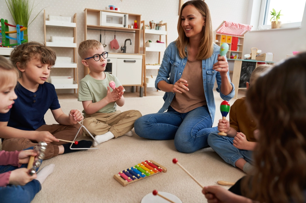GettyImages-2201772644 (1) (6) Children and teacher playing musical instruments together.