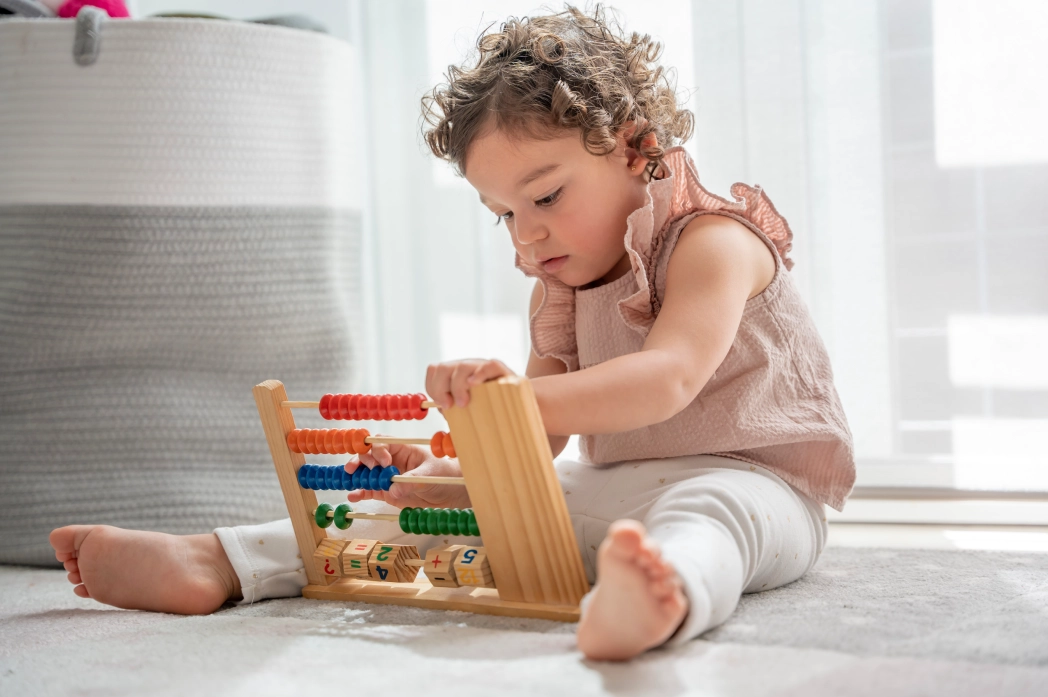 Child playing with colorful wooden abacus.