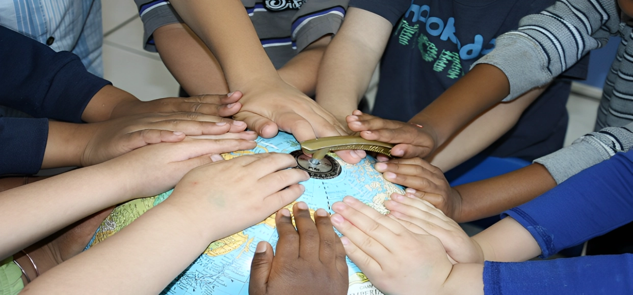 A group of people holding hands around a globe.
