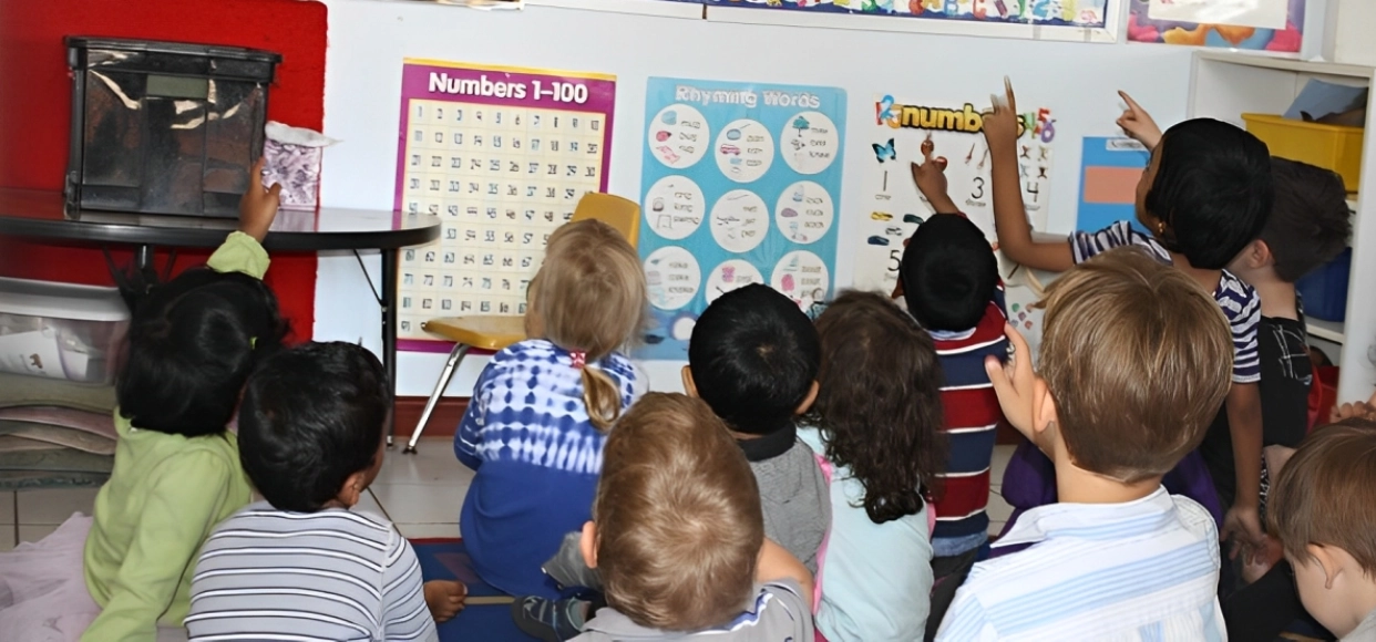 Children pointing at educational posters in classroom.