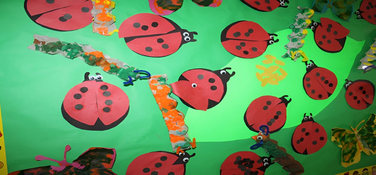 Paper ladybugs on a colorful green background.